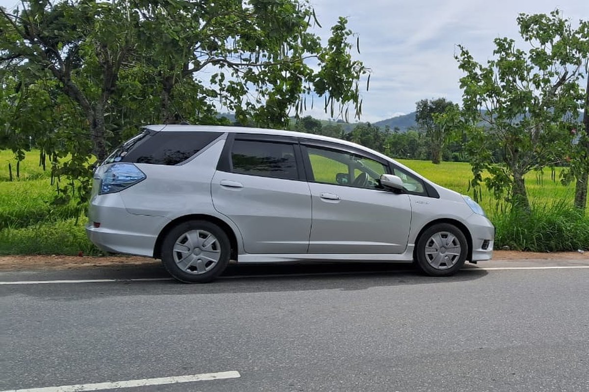 A Grace Lanka Tours vehicle on a rural Sri Lankan road, paddy fields and hill country in the distance