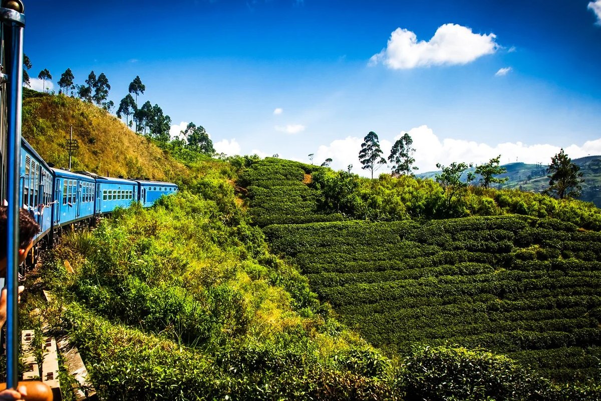 Nine Arches Bridge with red train crossing lush green hills in Ella, Sri Lanka